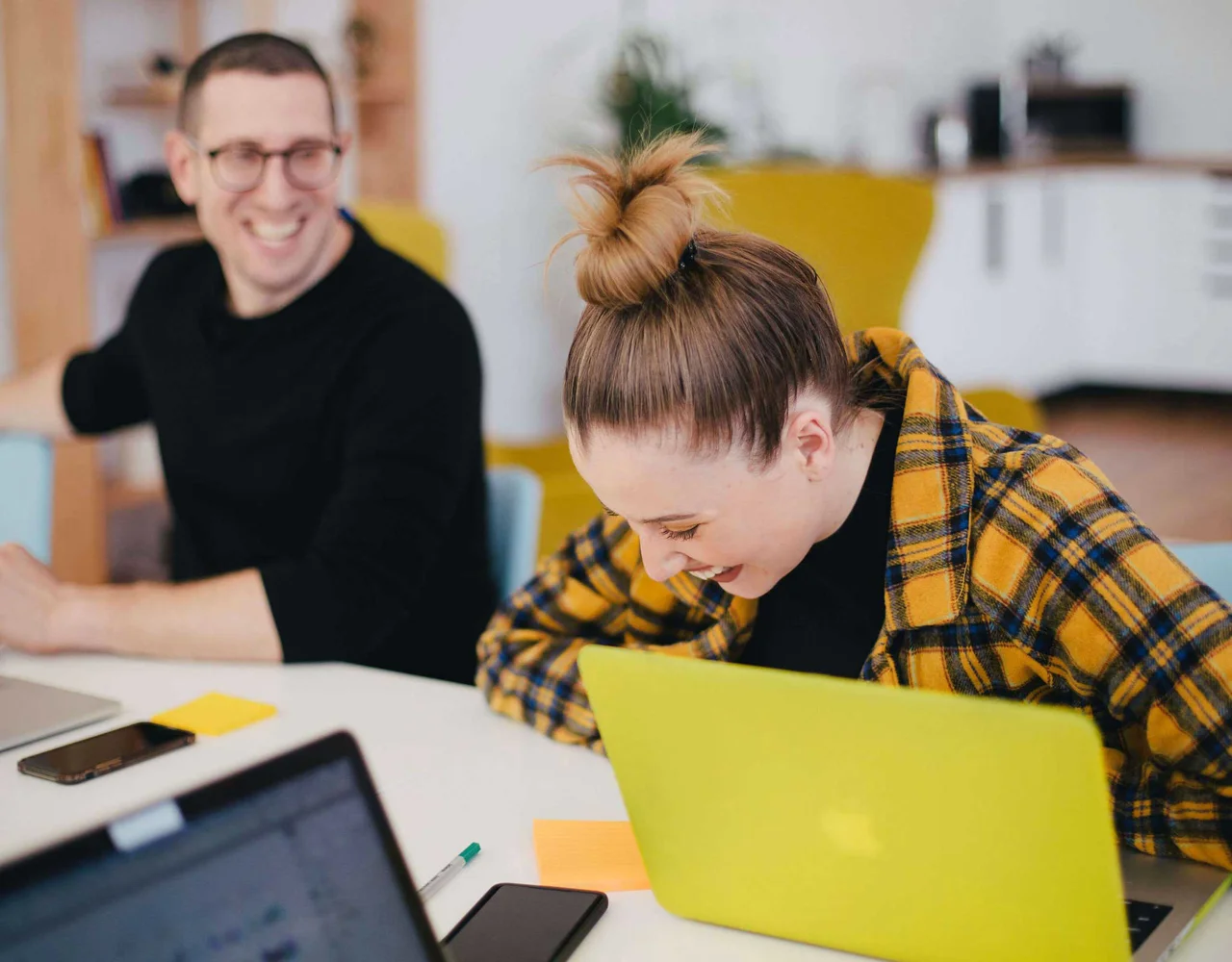 Man laughing looking at a girl who is bend over laughing
