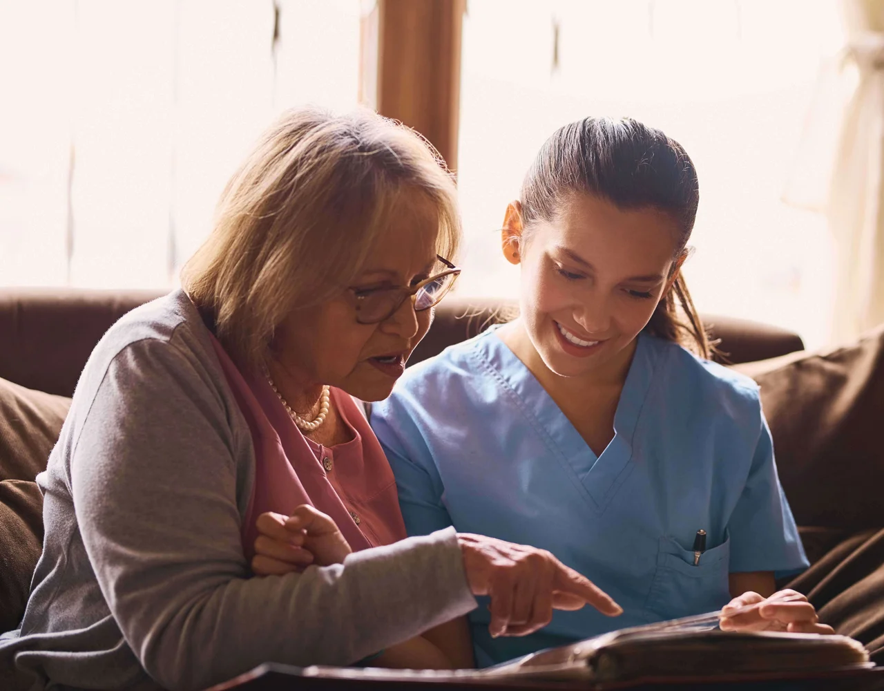 Health professional and women sat together looking at a book