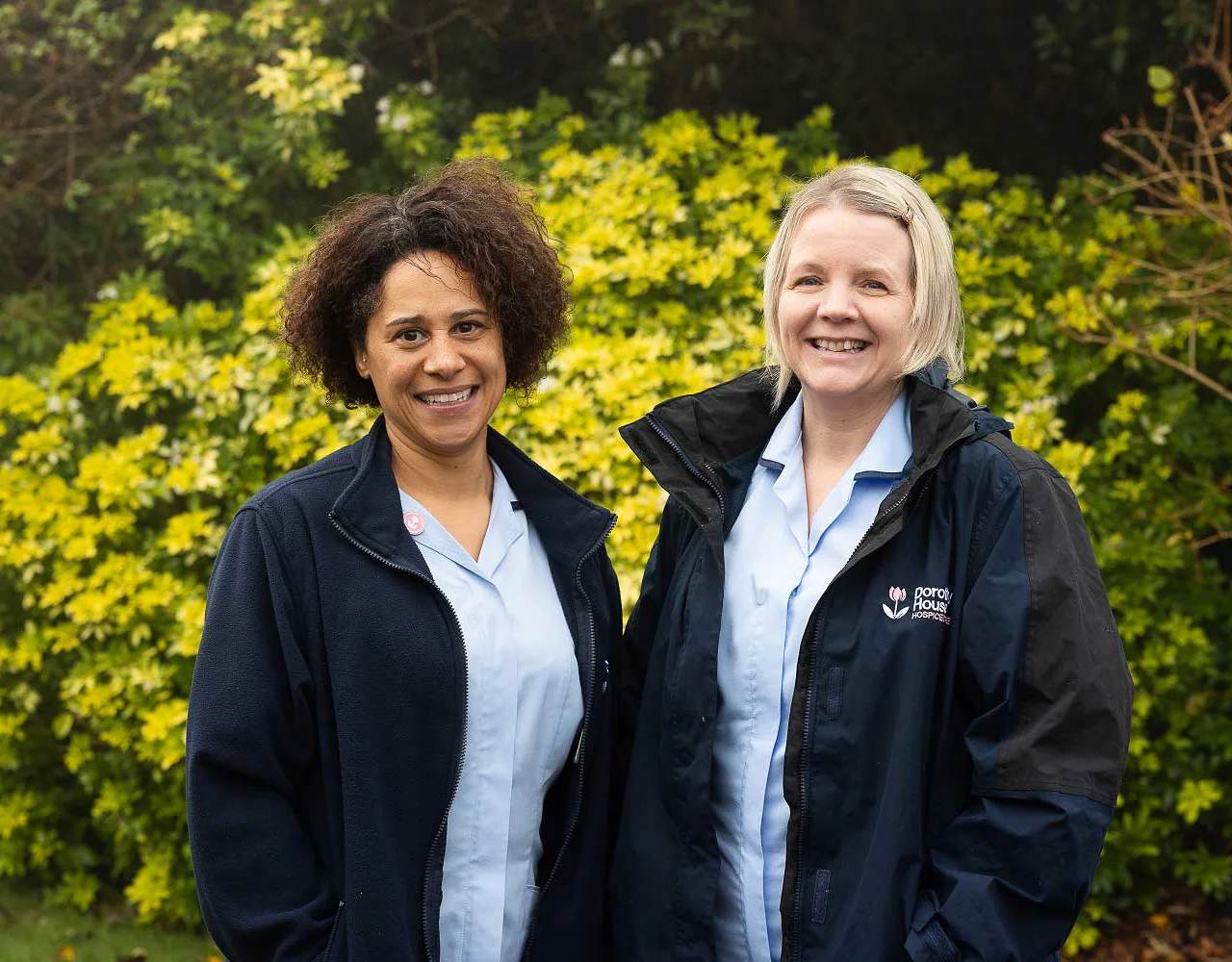 Two women who are carers standing smiling at the camera