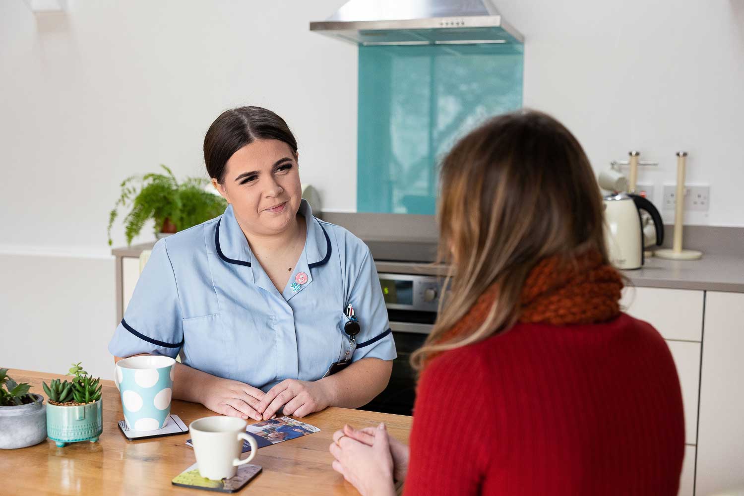 Women in uniform sat at a table with a women sat facing her with her back to the camera