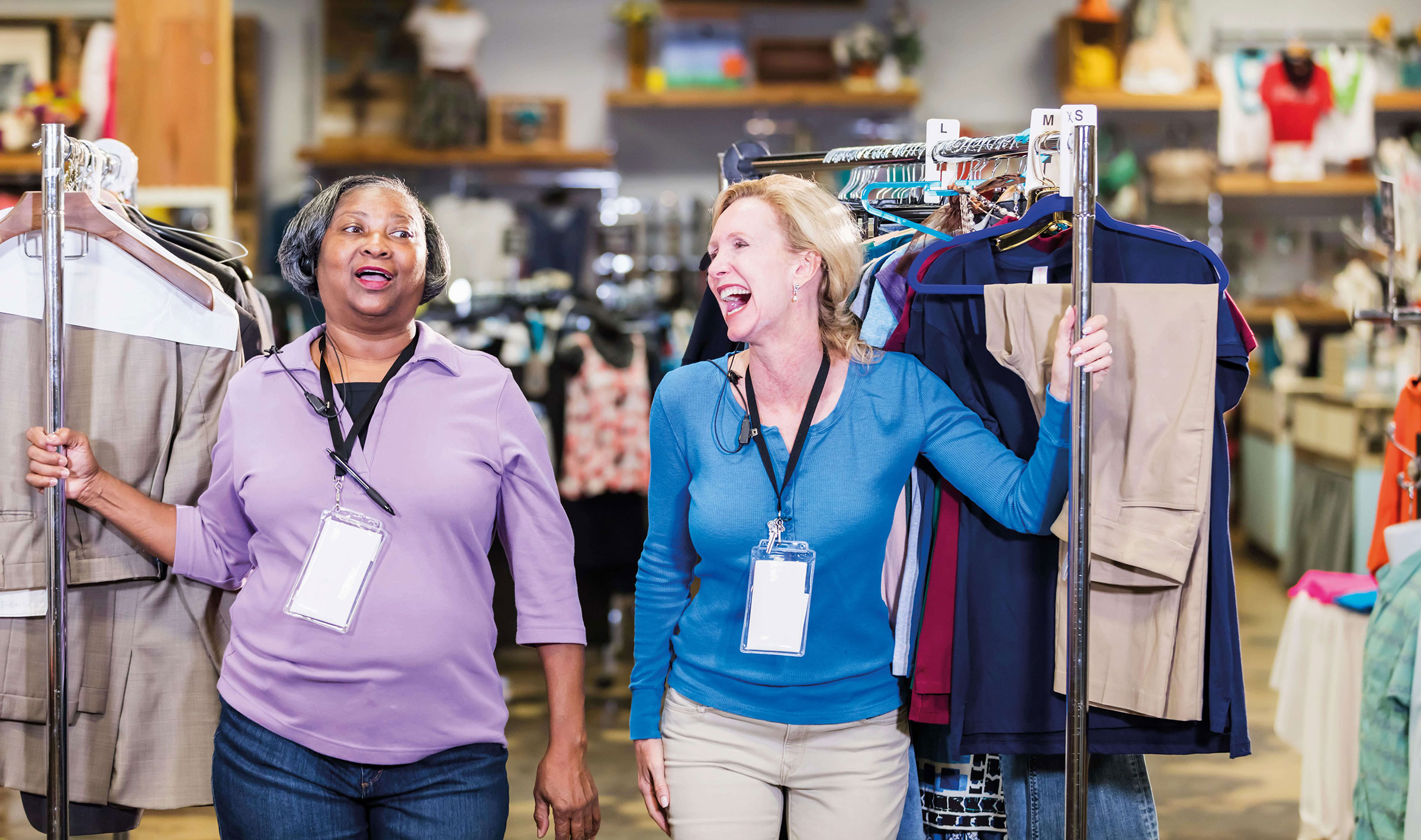Two women chatting and laughing while pulling clothing racks