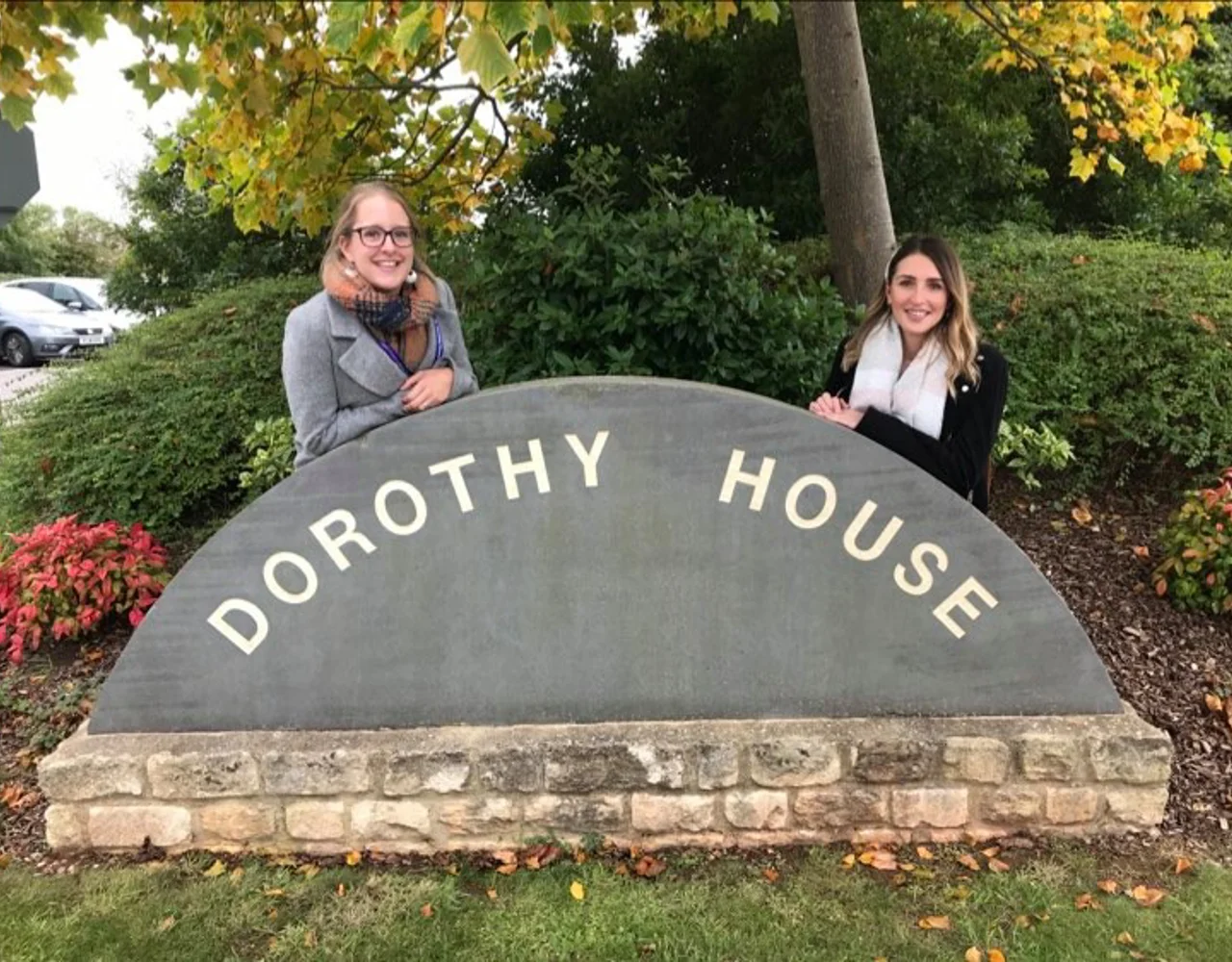 Two women stood behind the Dorothy House stone sign