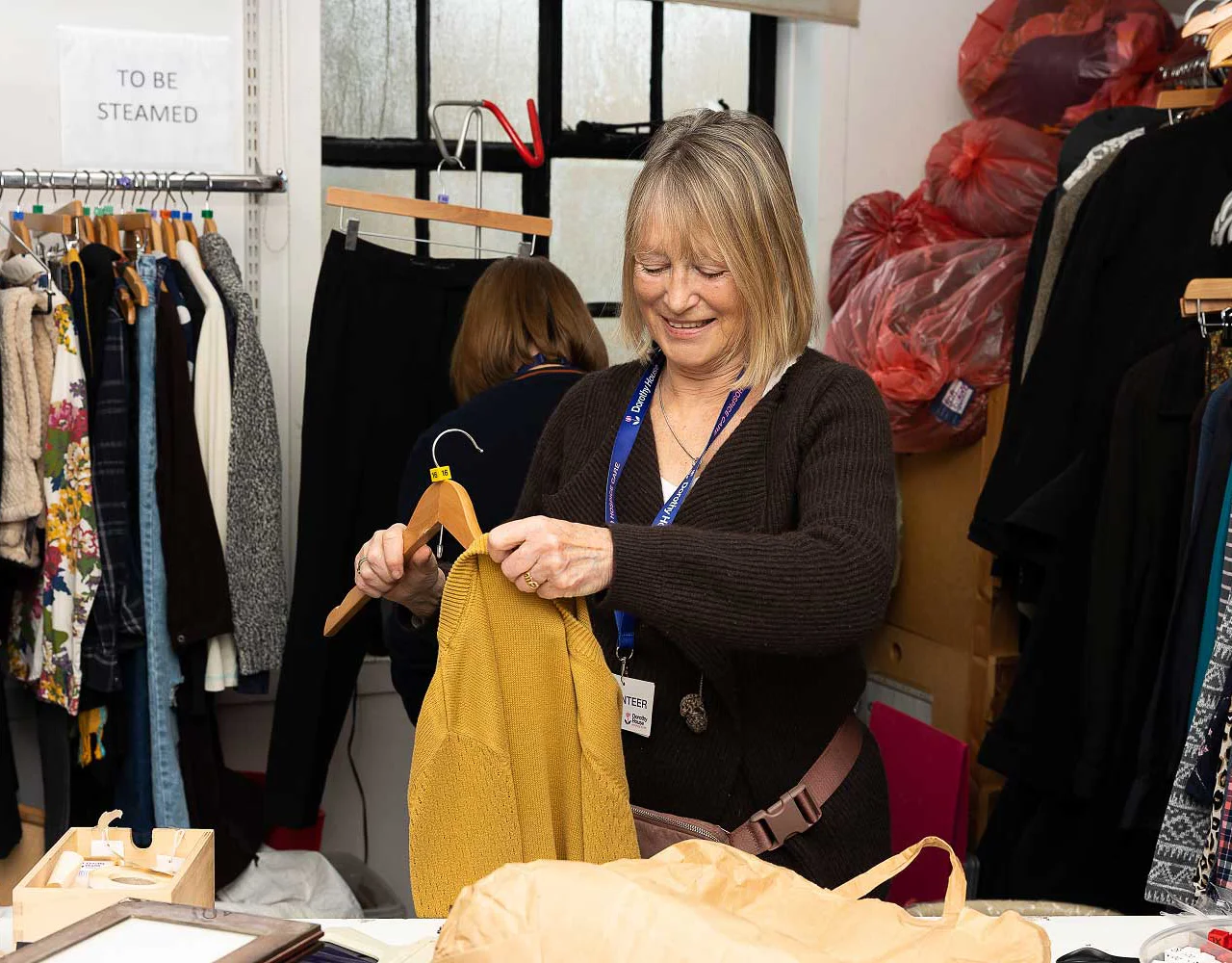 Women in a shop putting a piece of clothing on a hanger